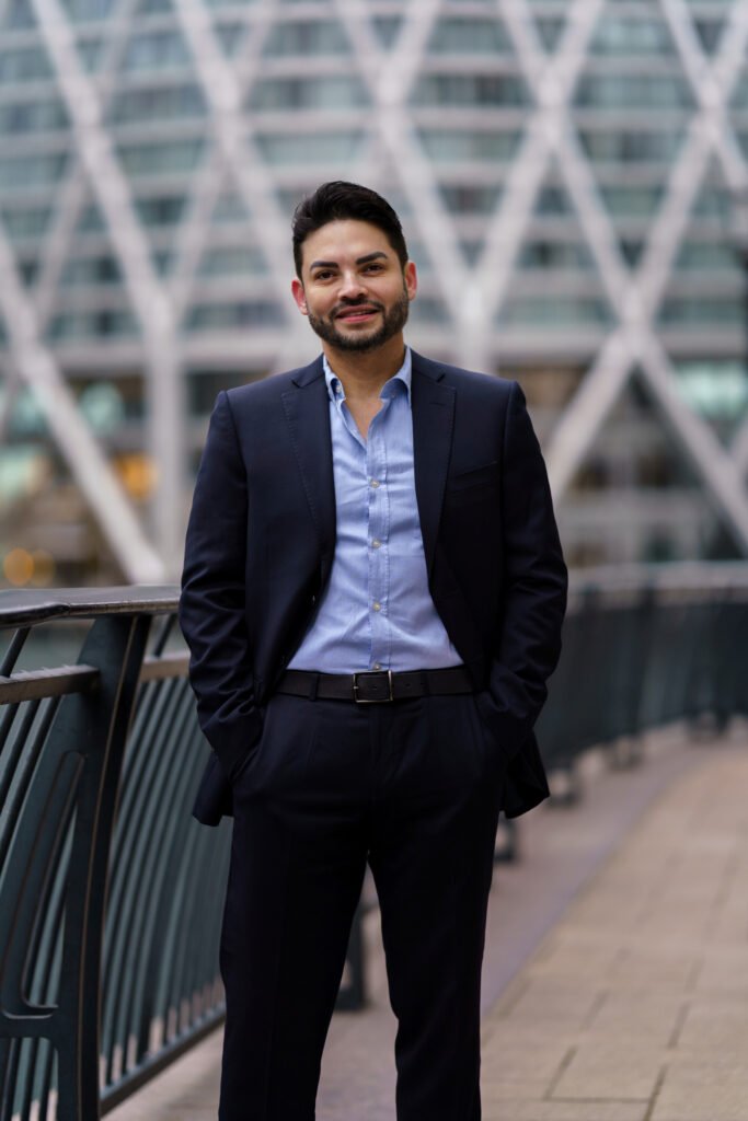 Ernesto Sanchez, founder of BRAVIEN, standing on a London footbridge in a navy suit